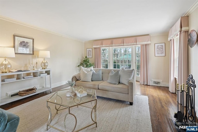 living area with visible vents, baseboards, wood finished floors, and crown molding