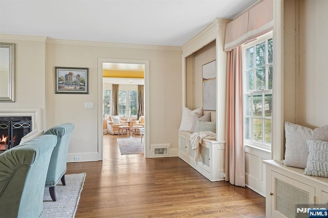 sitting room with visible vents, crown molding, baseboards, and wood finished floors