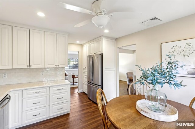 kitchen with visible vents, backsplash, white cabinetry, appliances with stainless steel finishes, and dark wood-style flooring