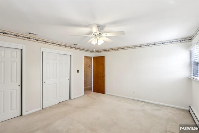 unfurnished bedroom with baseboards, visible vents, a baseboard radiator, multiple closets, and light carpet