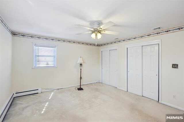 unfurnished bedroom with visible vents, carpet floors, baseboards, multiple closets, and a baseboard heating unit