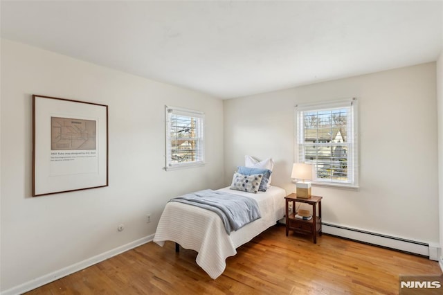 bedroom with light wood-style flooring, baseboards, and a baseboard radiator