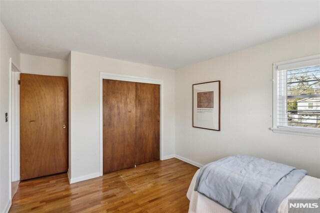 bedroom featuring light wood-style floors, baseboards, and a closet