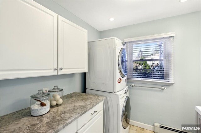 clothes washing area with baseboards, recessed lighting, cabinet space, stacked washer and dryer, and baseboard heating