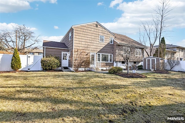 back of house with a lawn, a storage shed, a fenced backyard, an outbuilding, and a gate