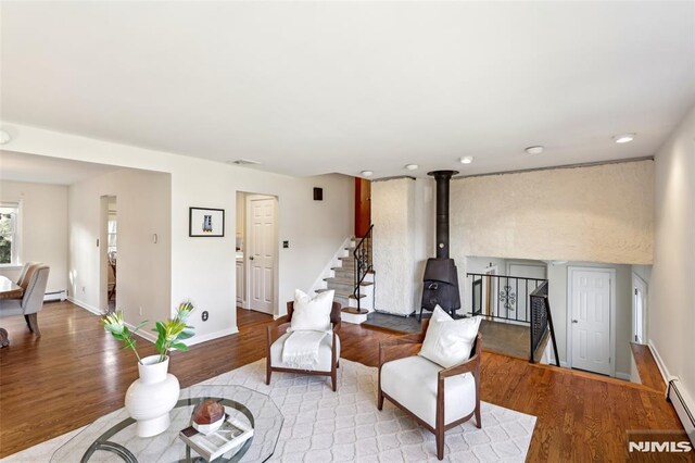 living area featuring visible vents, a baseboard heating unit, wood finished floors, baseboards, and stairs