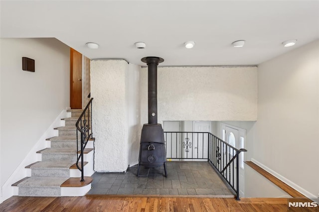 stairway with a wood stove, wood finished floors, and baseboards