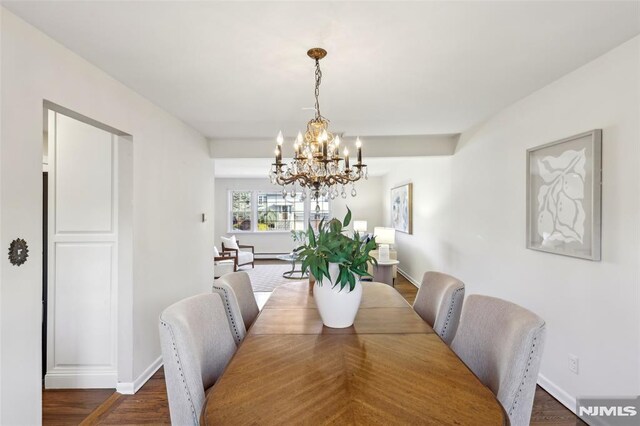 dining area featuring dark wood finished floors, baseboards, and a chandelier