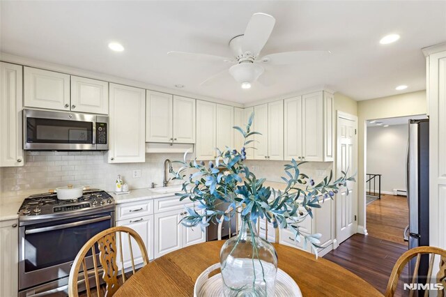 kitchen featuring tasteful backsplash, appliances with stainless steel finishes, light countertops, and a sink