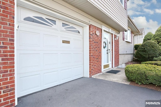 doorway to property featuring aphalt driveway and brick siding