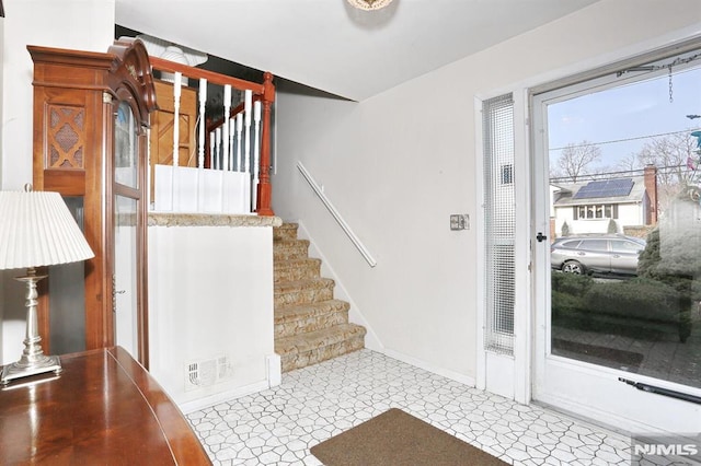 foyer entrance featuring visible vents, stairs, and baseboards