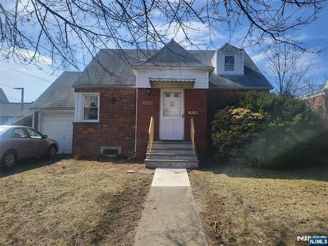 view of front facade featuring a front yard, an attached garage, and brick siding