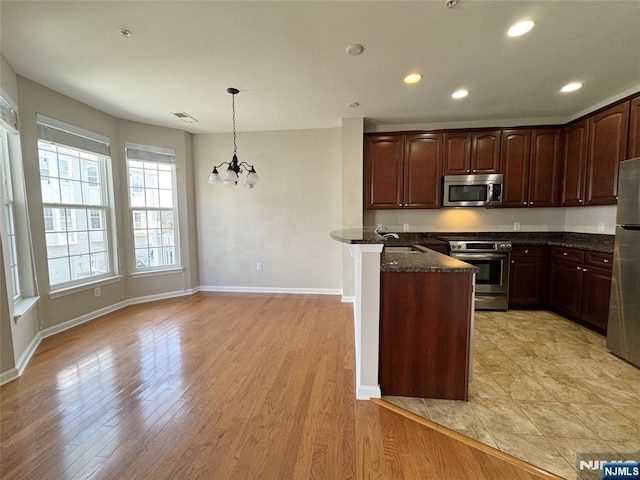 kitchen featuring dark stone countertops, recessed lighting, light wood-type flooring, and stainless steel appliances