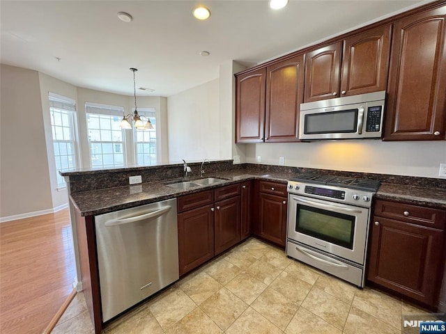 kitchen featuring a chandelier, dark stone countertops, a peninsula, stainless steel appliances, and a sink