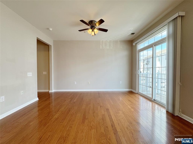 empty room featuring light wood-style flooring, a ceiling fan, and baseboards