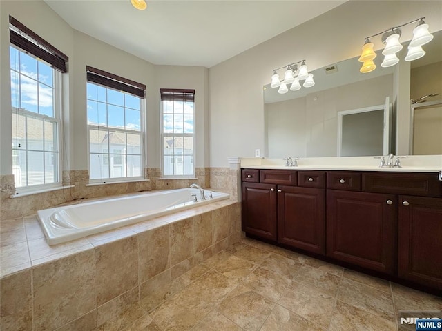 bathroom featuring a sink, visible vents, a bath, and double vanity