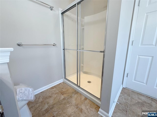 full bathroom with a shower stall and baseboards