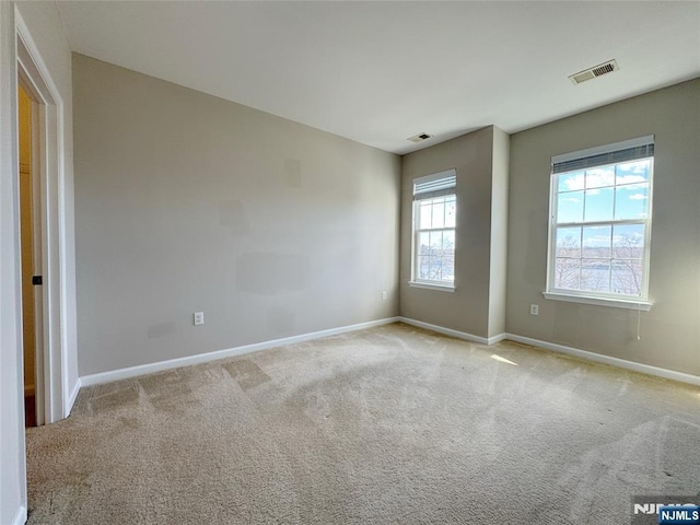 carpeted empty room featuring visible vents and baseboards