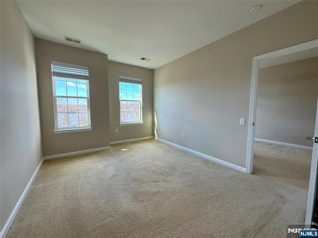 carpeted empty room featuring baseboards and visible vents