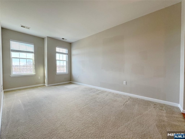 empty room with visible vents, baseboards, and light colored carpet