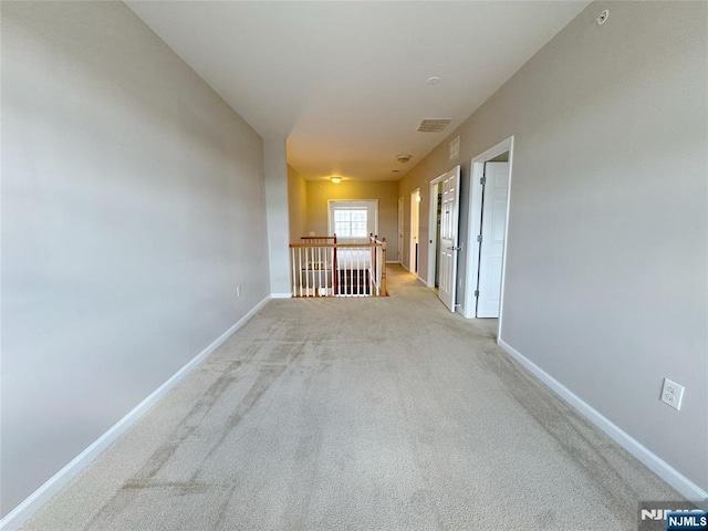 hall featuring visible vents, light colored carpet, and baseboards