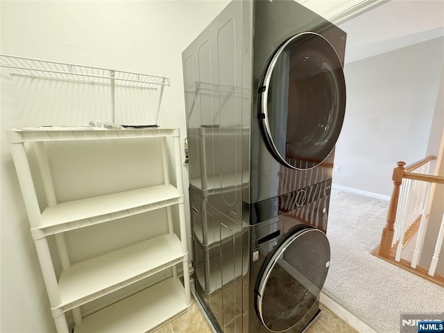 clothes washing area featuring baseboards, laundry area, carpet flooring, and stacked washing maching and dryer