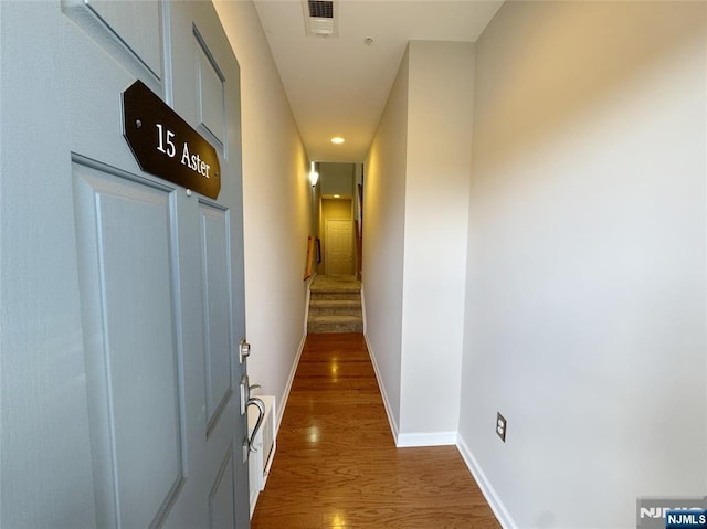 hall with stairs, wood finished floors, visible vents, and baseboards