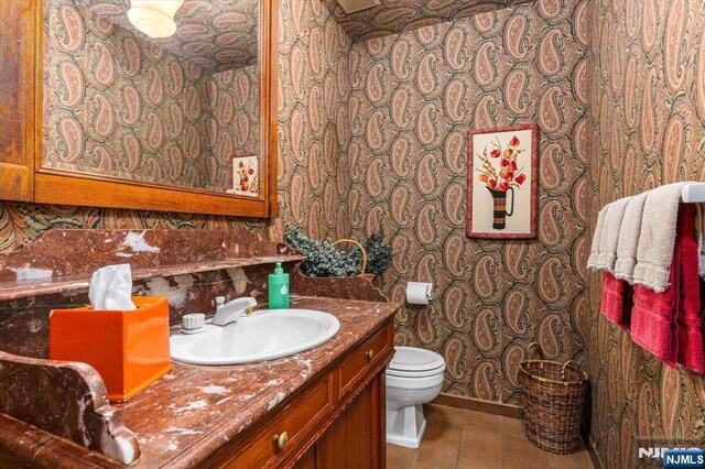 half bathroom with tile patterned floors, toilet, and vanity