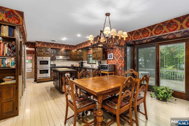 dining area with visible vents, a notable chandelier, light wood-style flooring, and wallpapered walls