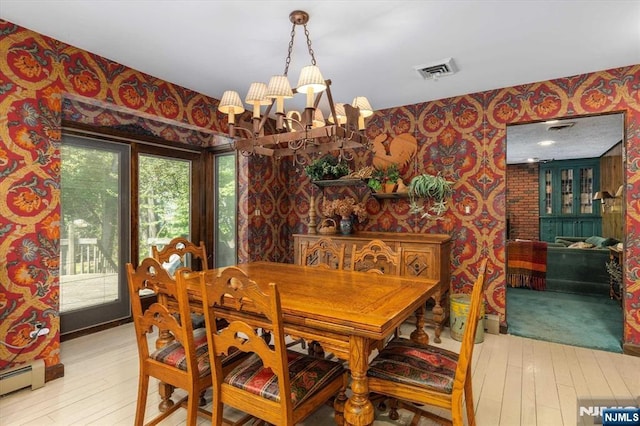 dining room featuring hardwood / wood-style floors, visible vents, a baseboard radiator, wallpapered walls, and an inviting chandelier