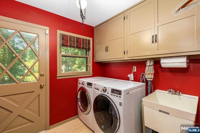 washroom with separate washer and dryer, cabinet space, light wood-style floors, and a sink