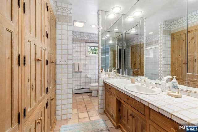 bathroom with vanity, a baseboard radiator, tile walls, toilet, and tile patterned floors