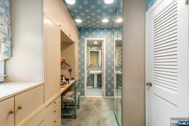 bathroom featuring wallpapered walls, baseboards, and a sink