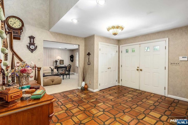 foyer entrance featuring wallpapered walls and baseboards