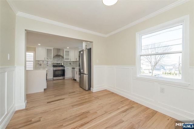 interior space with light wood finished floors, a healthy amount of sunlight, and ornamental molding