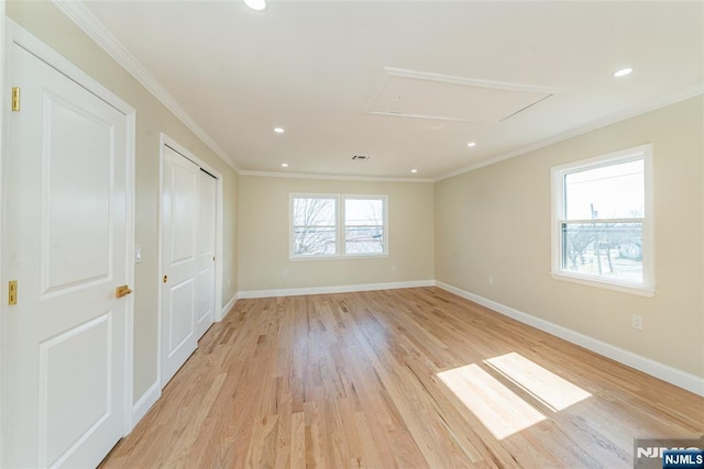 spare room featuring attic access, crown molding, and baseboards