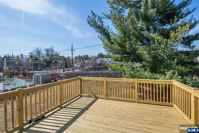 wooden terrace featuring an outbuilding, a storage unit, and a fenced backyard