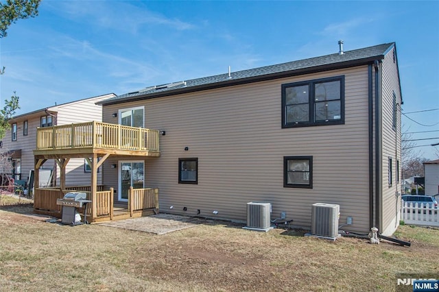 rear view of house featuring cooling unit, a lawn, a deck, and fence