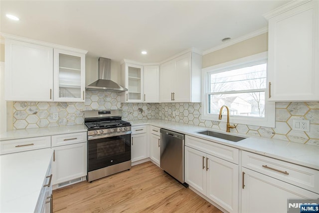 kitchen with visible vents, a sink, light wood-style floors, appliances with stainless steel finishes, and wall chimney range hood