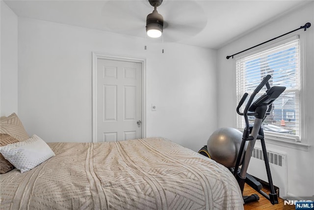 bedroom with radiator, wood finished floors, and ceiling fan