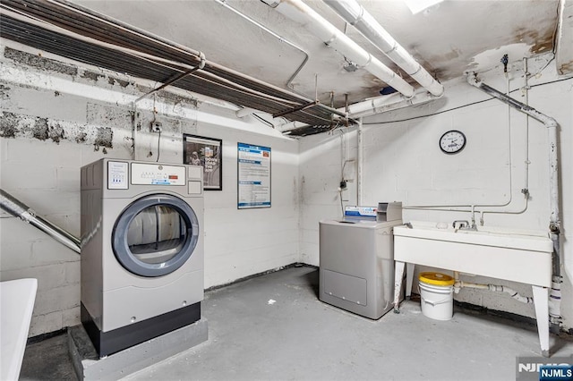 clothes washing area with a sink, washer / clothes dryer, concrete block wall, and laundry area