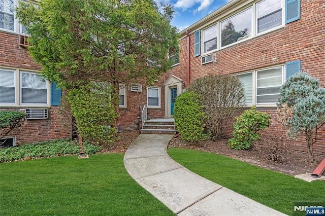 entrance to property featuring a yard and brick siding