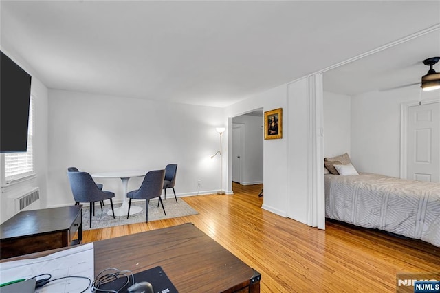 bedroom featuring baseboards, light wood-style flooring, and radiator heating unit