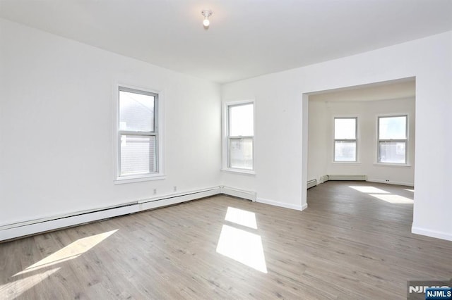 empty room with wood finished floors, baseboards, baseboard heating, and a baseboard radiator