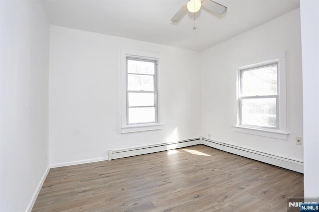 spare room with plenty of natural light, wood finished floors, baseboards, and a baseboard radiator