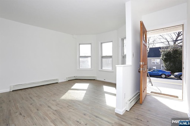 unfurnished room featuring a baseboard heating unit, plenty of natural light, and a baseboard radiator