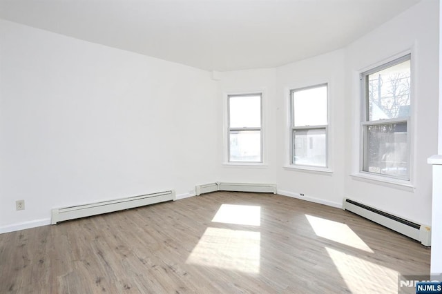 unfurnished room featuring baseboard heating, wood finished floors, and a baseboard radiator