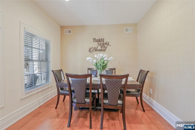 dining space featuring visible vents, light wood-style flooring, and baseboards