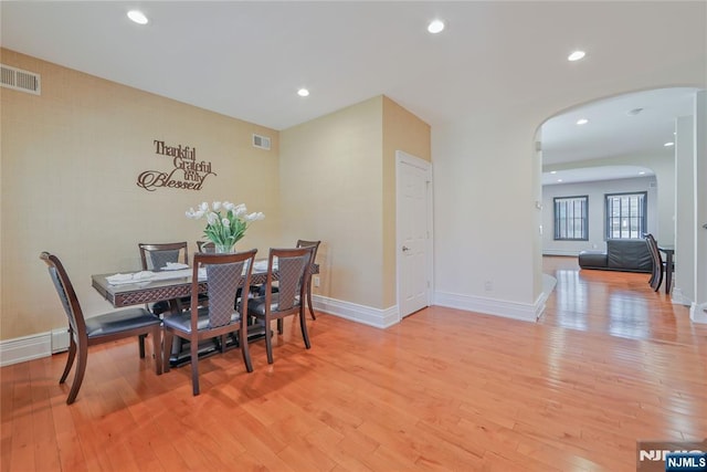 dining space with arched walkways, visible vents, light wood-style flooring, and recessed lighting