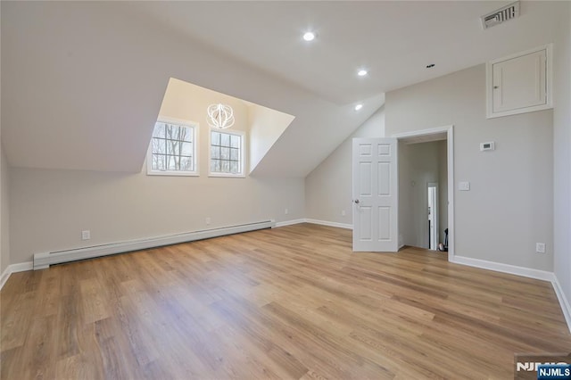 additional living space with visible vents, baseboards, light wood finished floors, lofted ceiling, and baseboard heating